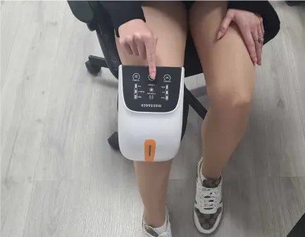 Person wearing Qinux Kneessa infrared knee massager at home